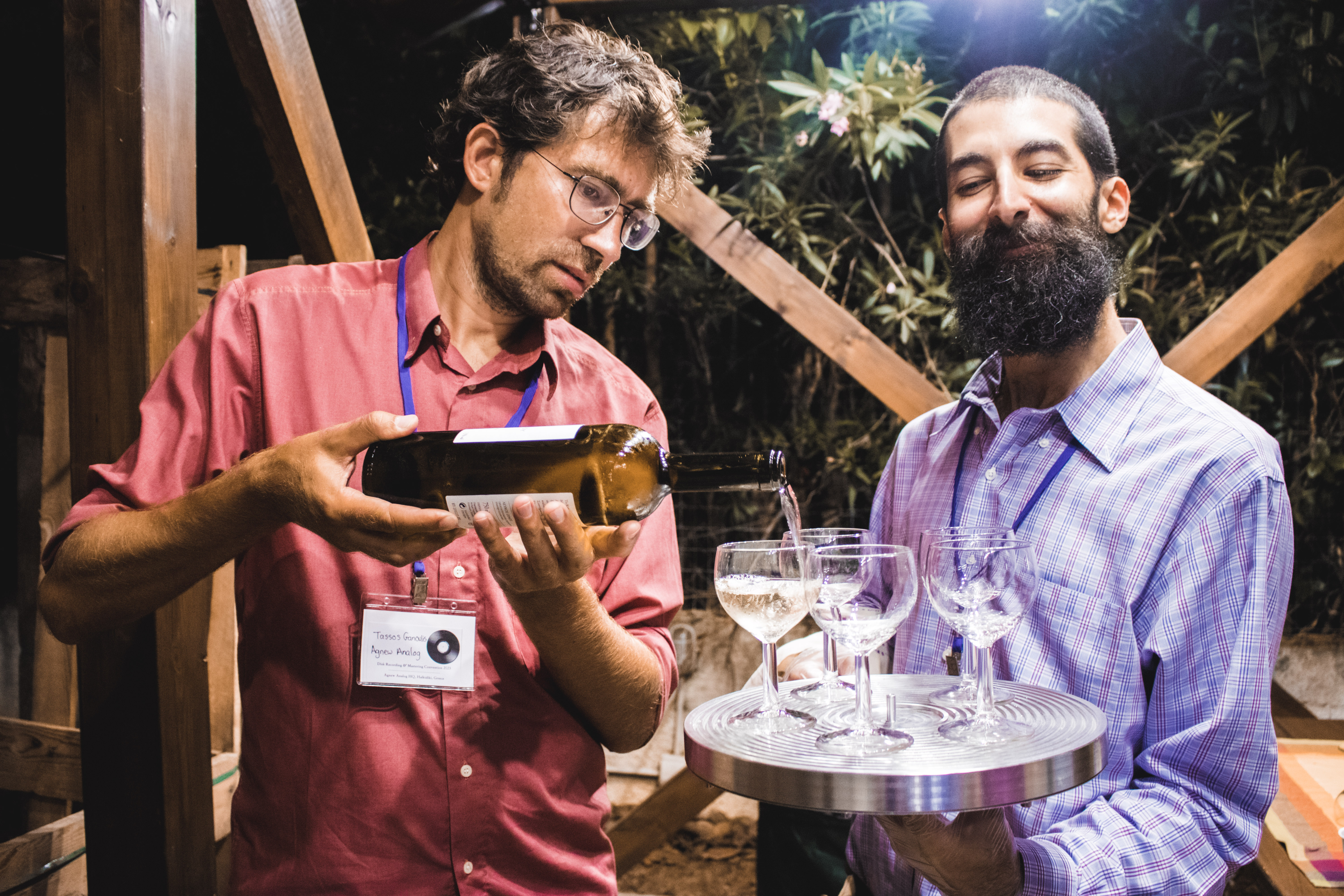 Tassos Ganoulis serving wine on a disk mastering lathe vacuum platter held by J. I. Agnew